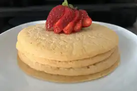 A stack of lentil pancakes with a sliced strawberry garnish on top.