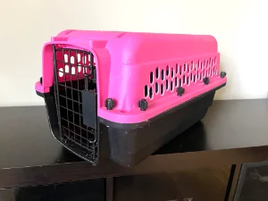 A sturdy and safe, pink and black cat carrier with screws holding the top and bottom half together.